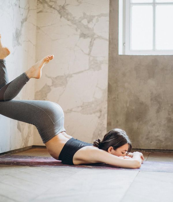 Woman practicing yoga pose in a dark ambient room with amber lighting.